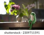 knitted frog toy on the table with lilac flowers