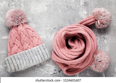 Knitted hat and scarf on grey background