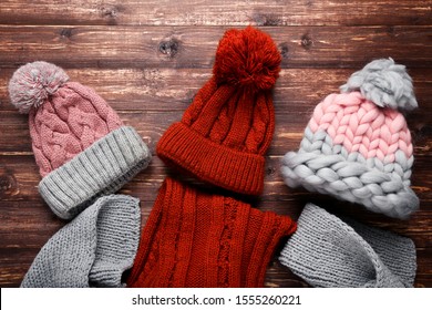Knitted hats and scarfs on brown wooden table