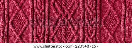 Knitted magenta background. Large knitted fabric with a pattern. Close-up of a knitted blanket. Demonstrating the colors of 2023 - Viva Magenta.