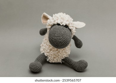 Knitted Sheep plush toy for children from white and gray yarn on gray background - Powered by Shutterstock