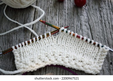 Knitted Swatch Of Cashmere Yarn On Bright Wood Needles Positioned On The Wood Table 