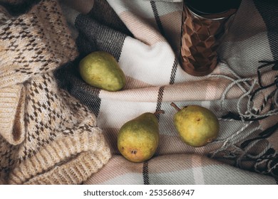 Knitted sweater, three pear fruits and thermos mug on checkered blanket in open car trunk. Autumn still life. Road trip picnic. Travel lifestyle moments. Fruits and coffee mug in trunk car. - Powered by Shutterstock