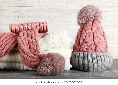 Knitted sweaters with scarf and hat on grey table