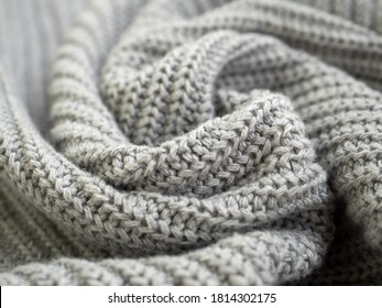 Knitted Warm Grey Sweater Or Scarf. Cozy Composition In The Home Atrosphere. Wool Fabric Texture Close Up Background. Comfortable Style Cloth. Wavy Folds Material. Soft Focus