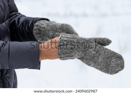 Knitted winter mittens.Warm gray mittens in women's hands.Warm clothes for walking outside in the cold season.