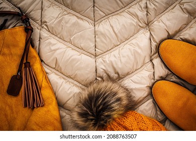 Knitted yellow hat , shoes, bag on Warm winter jacket with modern quilted pattern. Yellow gold Down jacket . Winter season fashion background.  - Powered by Shutterstock