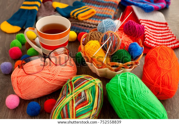 Knitting and comfort. Balls of\
yarn, knitting needles, basket, tea, glasses provide comfort during\
knitting. Yarn and knitting needles for making knitted clothes.\
