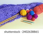 Knitting concept. Colorful balls of wools, knitted shawl, knitting  needles and сrochet hooks. Copy space