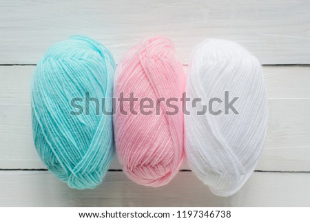 knitting hank in line on white wooden background, pastel blue, pink and white colors, close up top view flat lay, stock photo image