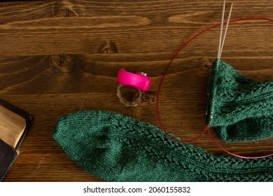 Knitting process, green woolen socks on wooden table