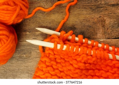 Knitting Project Over Wooden Background. Big Knits And Big Knitting Needles