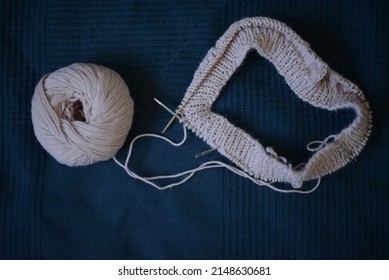 Knitting Project In Pale Pink Color, Seen On A Dark Blue Background