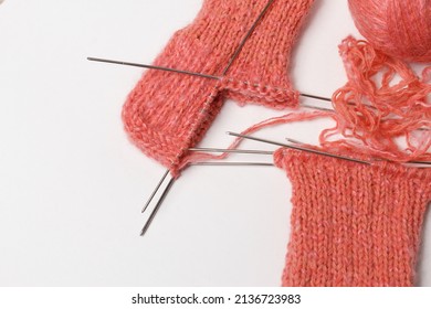 The knitting project is under implementation. A piece of knitting with a ball of yarn and knitting needles on a white background