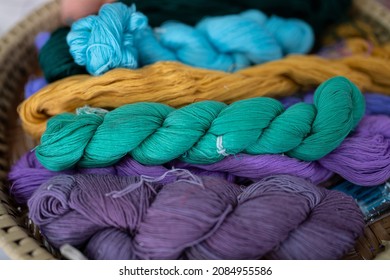 Knitting yarn in balls. In a wicker basket, balls of yarn for knitting. Coziness is created by a cup of tea, a knitting yarn, and knitted clothing. Knitting yarn with a rainbow of colors.