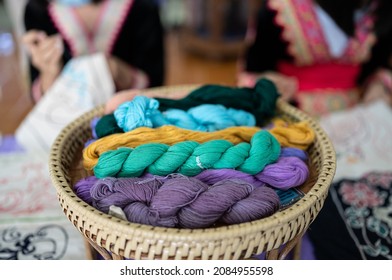 Knitting yarn in balls. In a wicker basket, balls of yarn for knitting. Coziness is created by a cup of tea, a knitting yarn, and knitted clothing. Knitting yarn with a rainbow of colors.