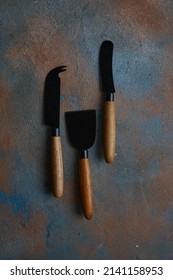 Knives for cheese on rust old heavily worn black navy blue concrete texture or background. With place for text and image