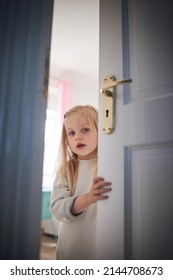 Knock Knock, Whos There. Shot Of An Adorable Little Girl Opening A Door At Home.