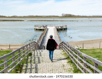 Knokke Heist, Flemish Region - Belgium - 04 03 2021  Active Woman Walking Down A Wooden Pier In A Coastside Nature Reserve