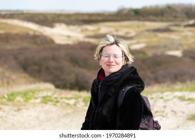 Knokke Heist, Flemish Region - Belgium - 04 03 2021: Thirty Year Old Woman Posing With The Dunes In The Background