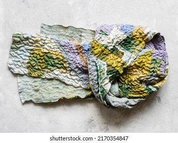 knotted patchwork scarf sewn from various crinkled silk fabrics on gray conctete backhround