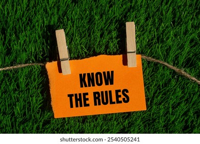 Know the rules message written on ripped torn orange paper piece with green grass background. Conceptual know the rules symbol. Copy space.