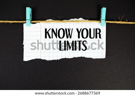 Know Your Limits text written on rip paper with wooden clip on black background