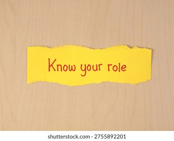 Know your role handwritten message on torn yellow paper on wooden desk. Represents job responsibility, teamwork, leadership, and professional boundaries