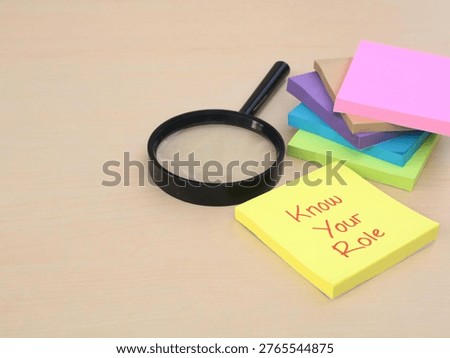 Know your role message on adhesive note with magnifying glass on wooden desk. Concept of self-awareness, professional responsibility, business ethics, and job performance evaluation