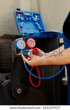 Knowleadgeable engineer calibrating manometers during comissioned outdoor hvac system monitoring. Seasoned mechanic looking for low refrigerant levels in air conditioner cooling system
