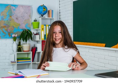 Knowledge Day. Child Pupil Sit At Table. Girl Is College Student. Back To School. Teen Girl Work In Classroom Near Blackboard. Cheerful Kid Learning Subject. Modern Education. Checking The Results