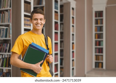 Knowledge. Excited caucasian male student posing next to bookshelves in campus library, empty space - Powered by Shutterstock