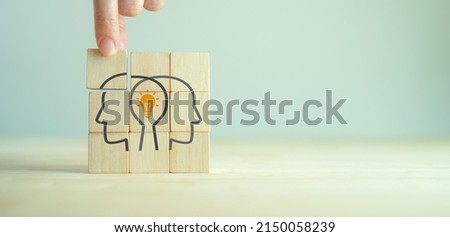 Knowledge and ideas sharing between two people head icon on wooden cube. Transferring knowledge, innovation, brainstorming concept. Business strategies to technology evolution reskill and new skill. 