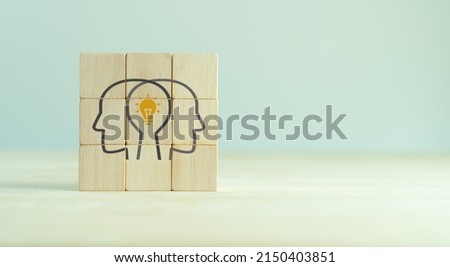 Knowledge and ideas sharing between two people head icon on wooden cube. Transferring knowledge, innovation, brainstorming concept. Business strategies to technology evolution reskill and new skill. 