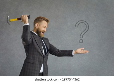 Knowledge Is Power. Young Businessman In Suit Is About To Hit Question Mark With Hammer. Man Aggressively Looking For Answer To Troubling Question Wants To Break Through Ignorance And Know The Truth