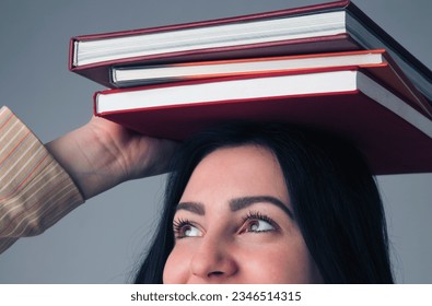 Knowledge,  self development and education concept. Portrait of young student girl balancing books on her head. Horizontal image.