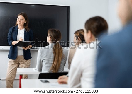 Knowledgeable female professor explaining subject to classroom full of students