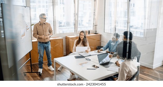 A knowledgeable mature leader facilitates a strategic discussion with a multicultural team, a calm and productive atmosphere, ideal for innovative thinking and inclusive decision-making