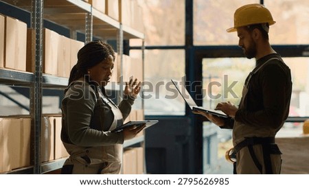 Knowledgeable workers performing warehouse inventory controls, discussing ways of keeping quality standards high. Certified experts preparing to ship parcels to customers, checking delivery info.