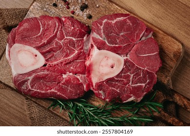 knuckle on the bone, raw meat for ossobuco, on a wooden chopping board, with a sprig of rosemary, and spices, top view, no people, - Powered by Shutterstock