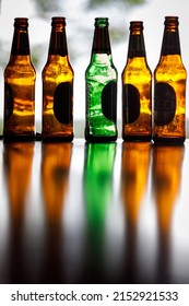 Ko Lanta, Ko Lanta District, Krabi 81150, Thailand  August 4th 2021 Backlit Beer Bottles In Green And Brown On A Shiny Dark Bar Surface With Strong, Colorful Reflections