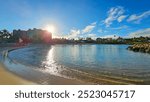 Ko Olina lagoon with blue ocean water, a sandy beach, lush green trees, plants and grass, blue sky and clouds at sunrise on the island of Oahu at the Ko Olina Resort in Kapolei Hawaii USA