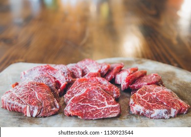 Kobe Steak. Sliced raw beef. Striploin steak on rustic wooden table. Fresh healthy tasty dry aged beef pieces. This is the best steak in the world.  Butchery products and butcher shop concept image.