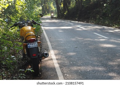 Kochi, Kerala - 1 December 2018 - A yellow colored Royal Enfield Continental GT motorcycle parked by the side of a highway. 