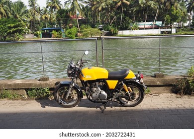 Kochi, Kerala - 21 July 2020 - A yellow Royal Enfield Continental GT 535 motorcycle parked along a barricade beside the backwaters in Kochi, Kerala