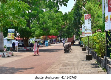 KOCHI, KERALA, INDIA, APRIL 30, 2016: Marine Drive - the picturesque promenade facing the backwaters. A favorite hangout for the locals and tourists. Woman walking with umbrella. Hot and sunny.