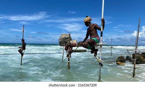 Koggala, Sri Lanka – April 30, 2022: Stilt Fishermen Fishing On A Stick On The Coast Of Koggala, Sri Lanka. 