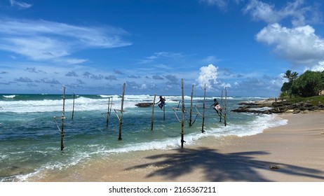 Koggala, Sri Lanka – April 30, 2022: Stilt Fishermen Fishing On A Stick On The Coast Of Koggala, Sri Lanka. 