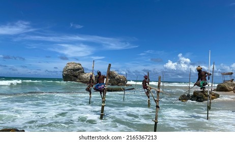 Koggala, Sri Lanka – April 30, 2022: Stilt Fishermen Fishing On A Stick On The Coast Of Koggala, Sri Lanka. 