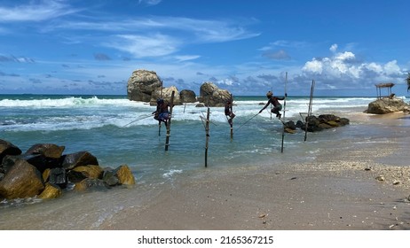 Koggala, Sri Lanka – April 30, 2022: Stilt Fishermen Fishing On A Stick On The Coast Of Koggala, Sri Lanka. 